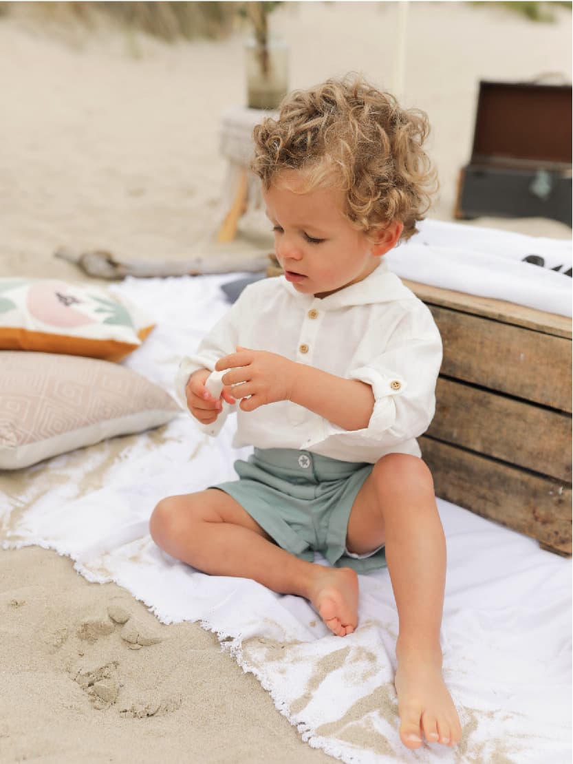 Petit garçon jouant dans le sable portant un short ou bermuda Berlingot